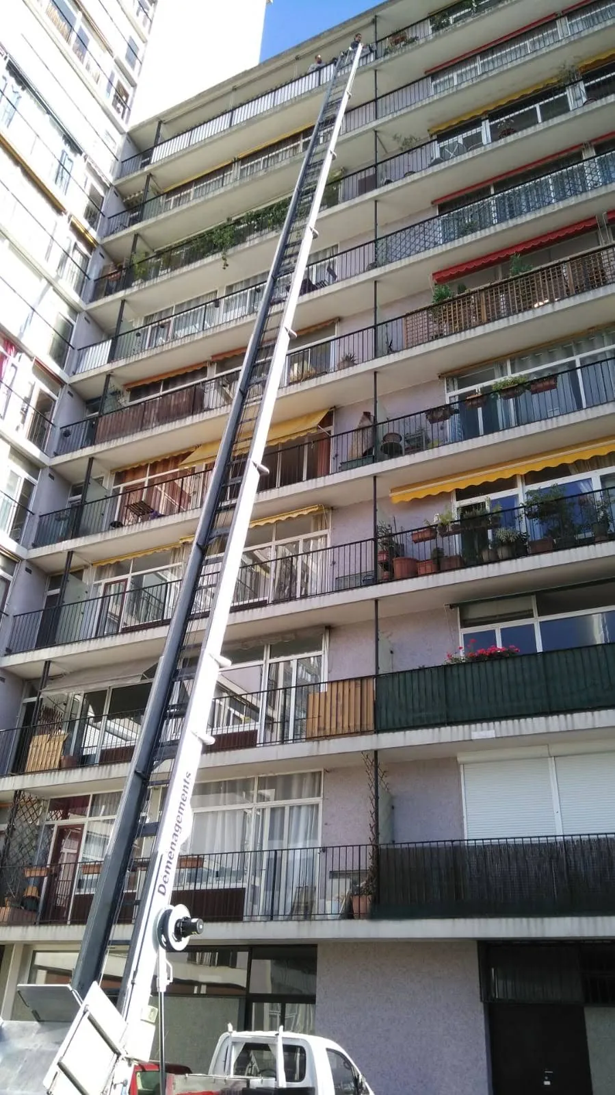Monte-charge déployé sur toute la hauteur d'un immeuble d'une dizaine d'étages à balcons